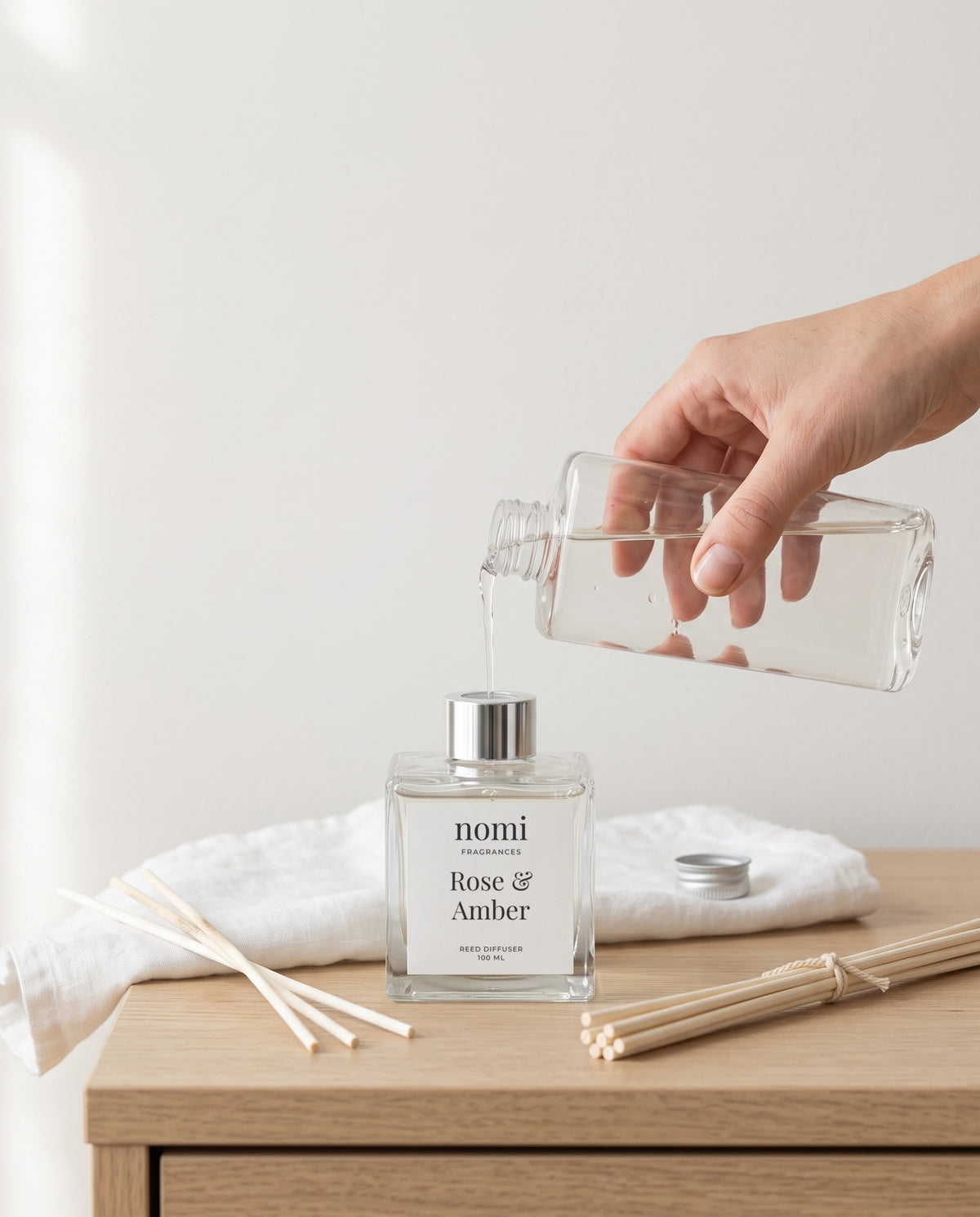 Pouring a nomi refill into a nomi reed diffuser bottle